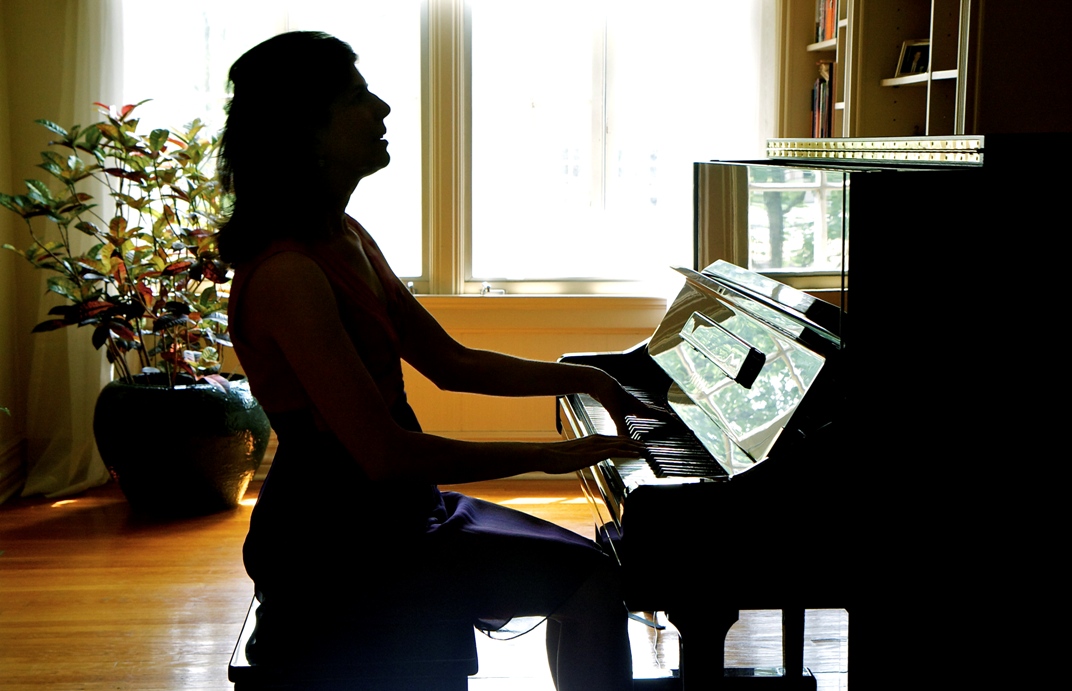 Shadowed Nancy Williams playing her home piano