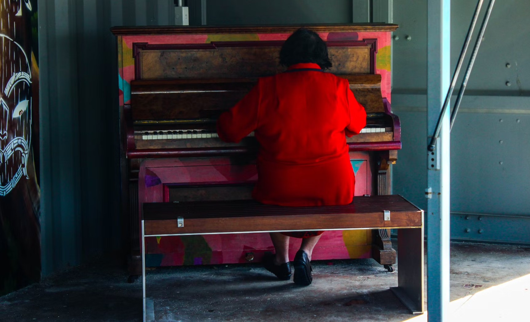 Elderly woman in red dress playing piano
