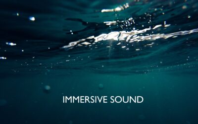 View of a lake underwater, with sunlight glinting on top, with the caption, "Immersive Sound"