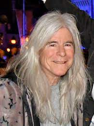 Photo of Dr. Nina Kraus leaning towards the camera and smiling. Her long, silver hair falls around her face and shoulders like a cloud.