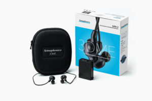 The 3DME in-ear monitors photographed next to their black padded case and the packaging, with an aqua blue background
